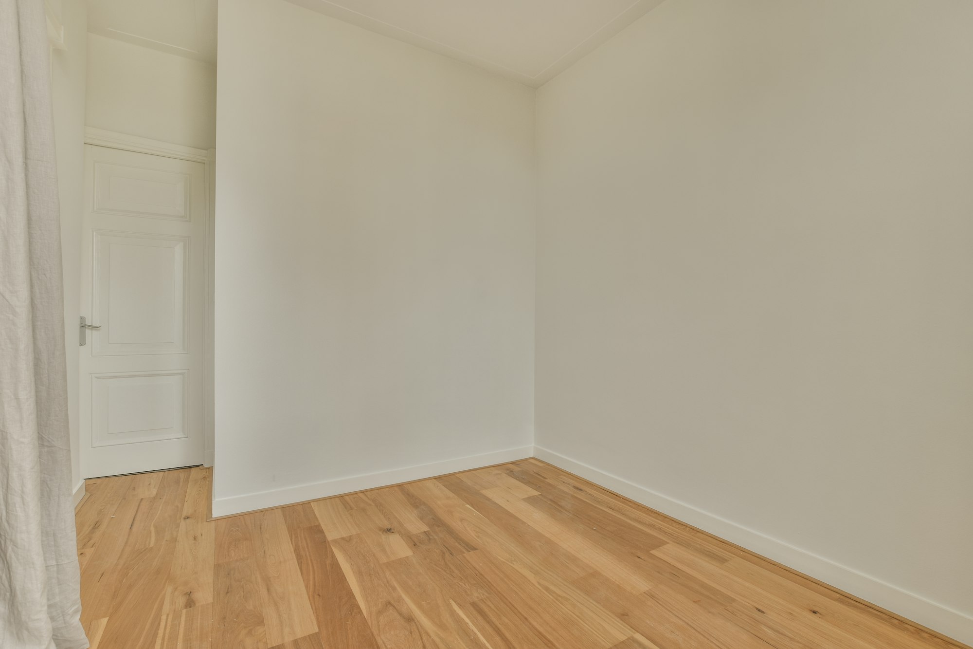 an empty room with white walls and wood flooring