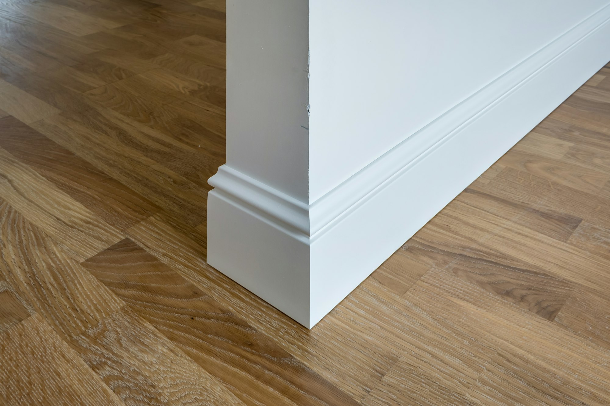 Detail of corner flooring with intricate crown molding and plinth.